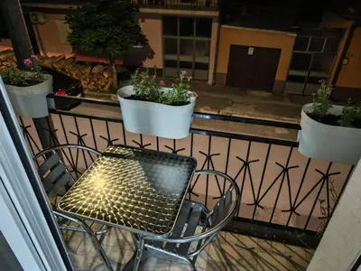 a table and chair on a balcony with potted plants at Studio D&I in Vranje