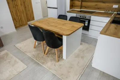 a kitchen with a wooden table and black chairs at Apartman Jelena in Vranje