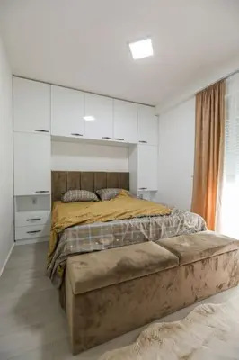 a bedroom with a bed in a white room at Apartman Jelena in Vranje