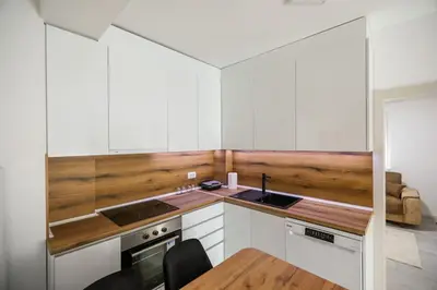 a kitchen with white cabinets and a wooden wall at Apartman Jelena in Vranje