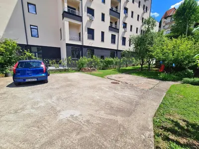 a blue car parked in a parking lot next to a building at Maja V Apartmani Sokobanja in Soko Banja