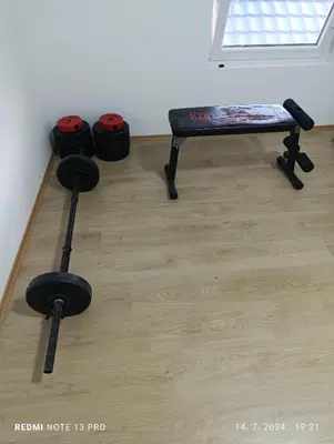 a room with a bench and dumbbells on the floor at Garfield Family Apartman 1 in Soko Banja