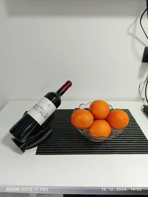 a bottle of wine next to a bowl of oranges at Garfield Family Apartman 1 in Soko Banja