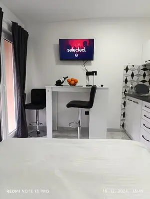 a kitchen with a table with two chairs and a tv on the wall at Garfield Family Apartman 1 in Soko Banja