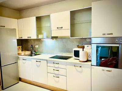 a kitchen with white cabinets and a stainless steel refrigerator at Apartman Family in Vrnjačka Banja