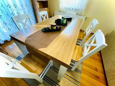 a wooden dining room table with white chairs and a table at Apartman Family in Vrnjačka Banja