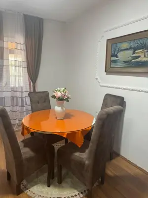 a dining room table with chairs and a vase with flowers on it at Jelena in Vranje