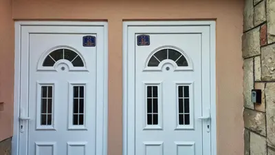 two white doors on the side of a building at Apartman Bagdala in Kruševac