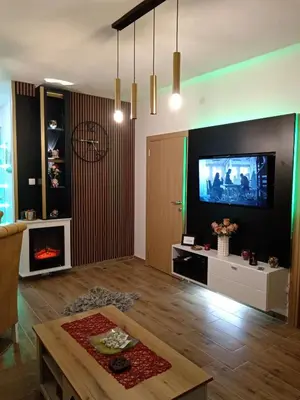 a living room with a fireplace and a tv on a wall at Apartman Tina , kod hotela Sunce in Soko Banja