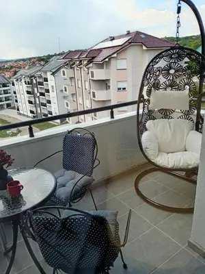 a balcony with chairs and a table and a swing at Apartman Tina , kod hotela Sunce in Soko Banja