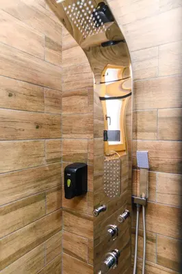 a bathroom with a shower with a wooden wall at SPA apartman Tomin adults only in Soko Banja
