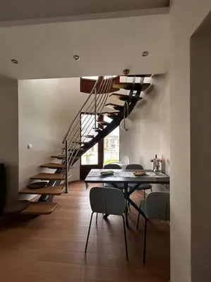 a living room with a staircase and a table and chairs at Royal King Villa 2 in Vrnjačka Banja