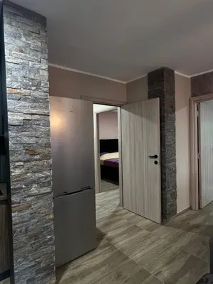 a living room with a stone wall and a refrigerator at Apartman Dašić in Jagodina