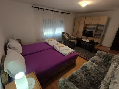 a living room with a purple bed and two chairs at Studio Petrović in Soko Banja