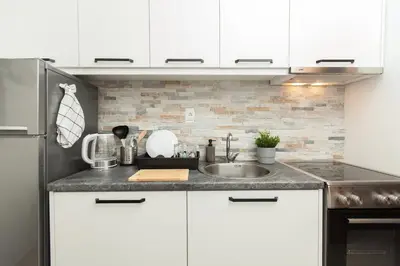 a kitchen with white cabinets and a sink at New Apartment in Vrnjačka Banja