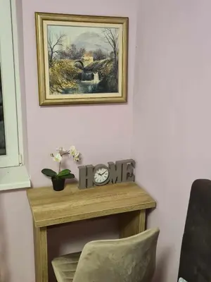 a table with a clock and a picture on the wall at Stan na dan Braca in Niš