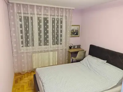 a bedroom with a bed and a window with a desk at Stan na dan Braca in Niš