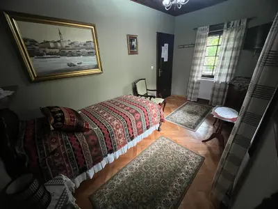 a bedroom with a bed and two rugs on the floor at Miletića čardak Ribarska Banja in Ribarska Banja