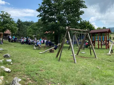 a group of people sitting in a park with a playground at Tomiceva Koliba Rtanj 2 in Rtanj