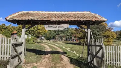 a wooden gazebo with a sign in a field at Tomiceva Koliba Rtanj 2 in Rtanj