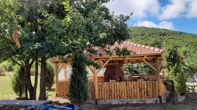 a wooden gazebo in a field with trees at Tomiceva Koliba Rtanj 2 in Rtanj
