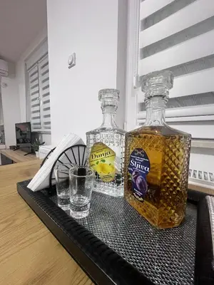 two bottles of honey and glasses on a table at Apartman Iva in Pirot