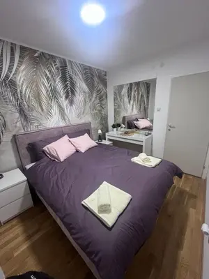 a bedroom with a bed with purple sheets and pink pillows at Apartman Iva in Pirot