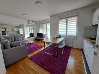 a kitchen and living room with a table and a couch at Apartman Iva in Pirot