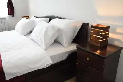 a bed with white pillows and a wooden night stand at Kod Bogdanovica in Vrtovac