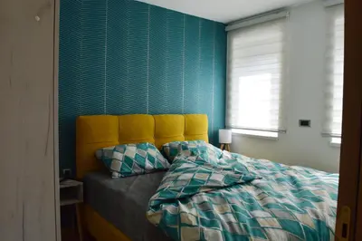 a bedroom with a bed with a yellow headboard at Apartman Ras in Vrnjačka Banja