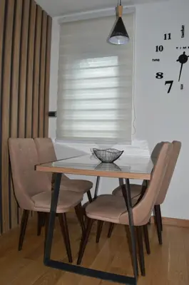 a dining room table with chairs and a clock on the wall at Apartman Ras in Vrnjačka Banja