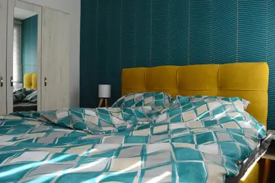 a bedroom with a bed with a blue and white comforter at Apartman Ras in Vrnjačka Banja