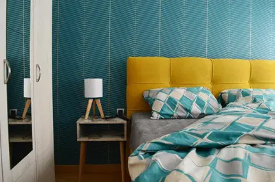 a bedroom with a bed with a yellow headboard and blue stripes at Apartman Ras in Vrnjačka Banja