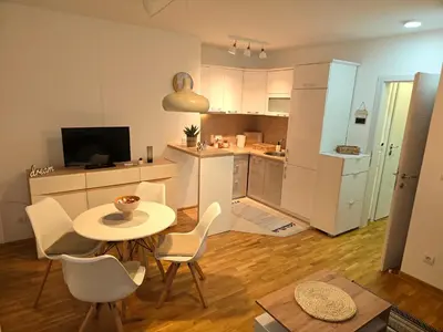 a living room with a table and chairs and a kitchen at Apartman Sorelle in Vrnjačka Banja