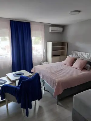 a bedroom with a large bed and a table at Apartments MIMOZA in Jagodina