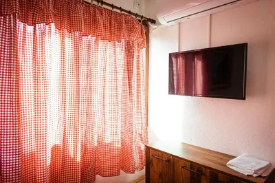 a red and white curtain in a room with a television at Porodična kuća Vitina Iža in Pirot