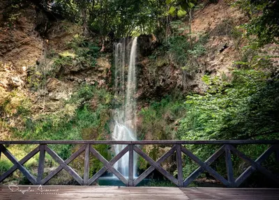 a waterfall behind a bridge in front of a waterfall at Restoran Lisine - Resavska pećina in Despotovac