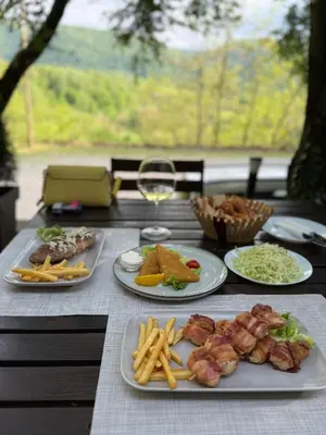 a table with plates of food and a glass of wine at Restoran Lisine - Resavska pećina in Despotovac