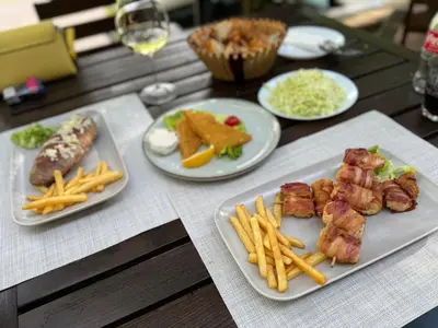 a table topped with plates of food and french fries at Restoran Lisine - Resavska pećina in Despotovac