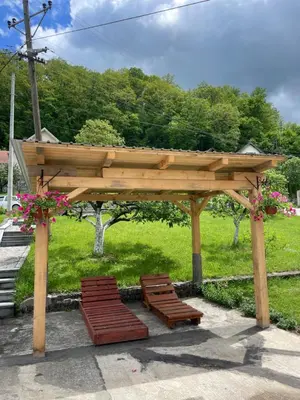 a wooden gazebo with two benches and flowers at Apartman Jošanička Banja in Jošanička Banja