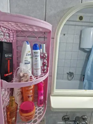 a pink rack with bottles of cosmetics in a bathroom at Jasemin in Ćuprija