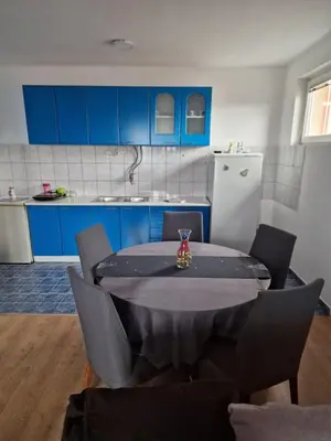 a kitchen with a table with chairs and blue cabinets at Jasemin in Ćuprija