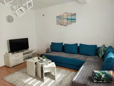 a living room with a blue couch and a tv at Apartman Magnolija in Vrnjačka Banja