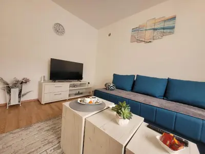 a living room with a blue couch and a tv at Apartman Magnolija in Vrnjačka Banja