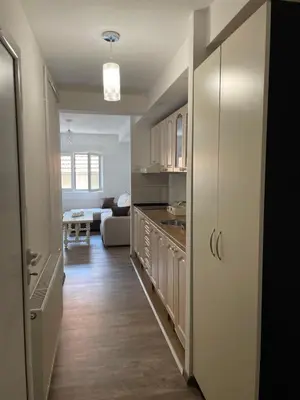 a kitchen with white cabinets and a living room at Apartmani Vrla NEW in Vladičin Han