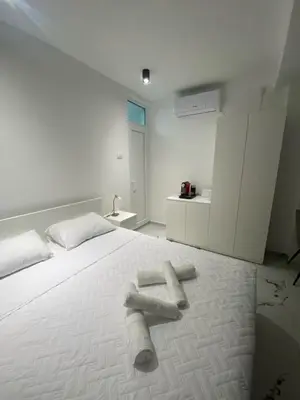 a white bed with two logs on top of it at Vito Apartman - Free Parking in Vranje