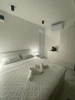 a white bedroom with a bed with two towels on it at Vito Apartman - Free Parking in Vranje