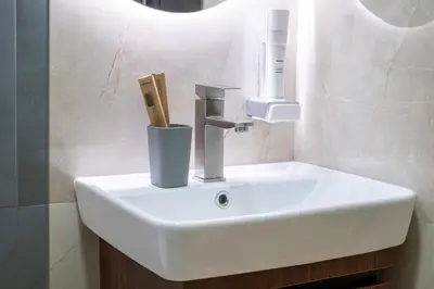 a bathroom sink with a soap dispenser on it at Trpeza Luxury Apartments, free parking in Niš
