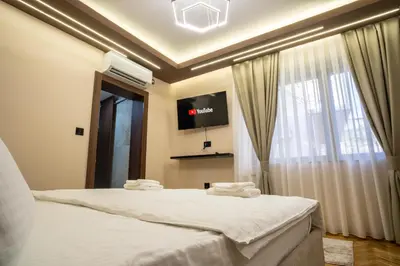 a bedroom with a bed with a tv and a window at Trpeza Luxury Apartments, free parking in Niš