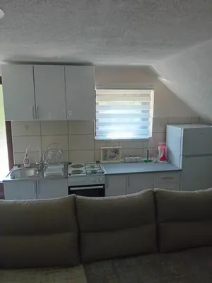 a kitchen with white cabinets and a couch in a room at Apartman Anči in Vrnjačka Banja